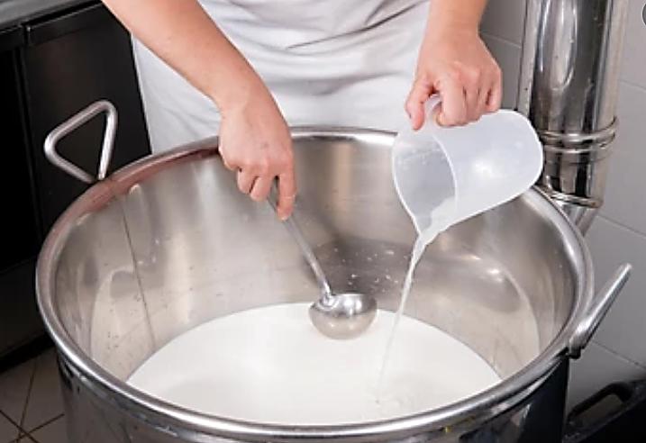 Fig. 1 Cheesemaker pours rennets into milk.